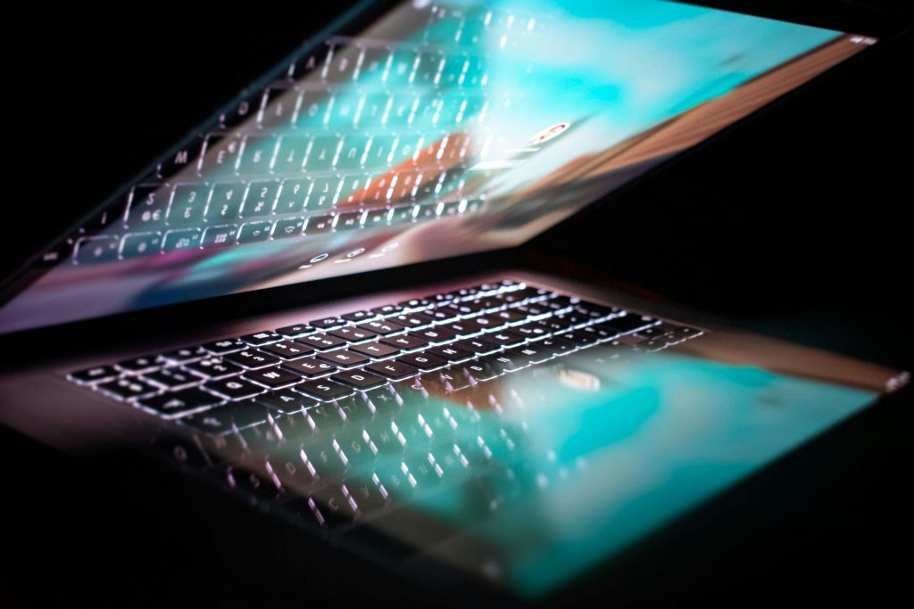 Close-up of a modern laptop with illuminated keyboard and colorful screen reflection.